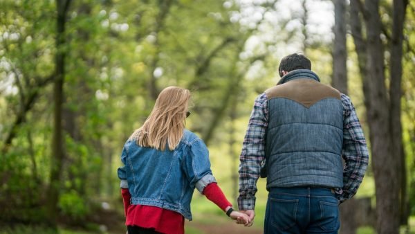 Happy couple walking hand in hand in the forest