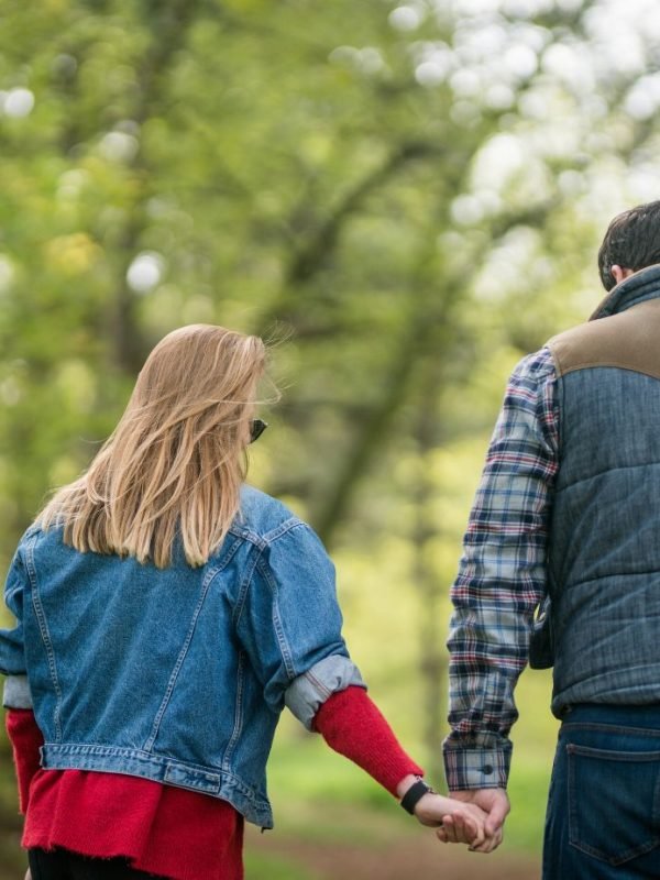 Happy couple walking hand in hand in the forest